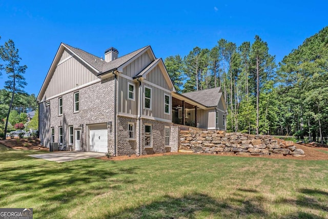 view of side of home with driveway, a yard, board and batten siding, brick siding, and a chimney