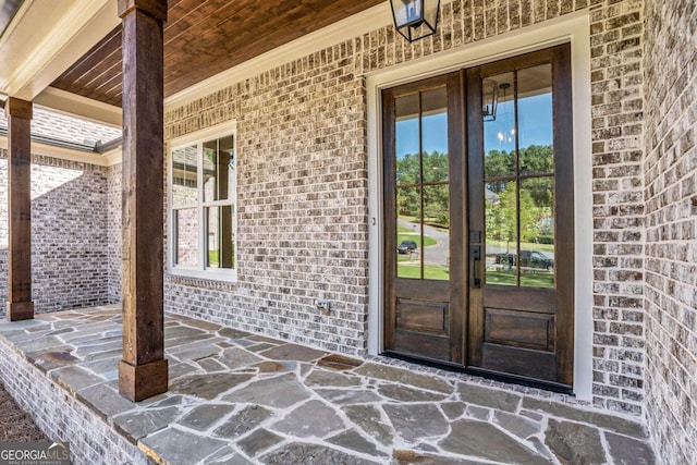 entrance to property featuring french doors and brick siding