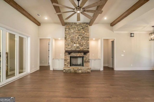 unfurnished living room featuring ceiling fan, beamed ceiling, dark wood-type flooring, and a fireplace