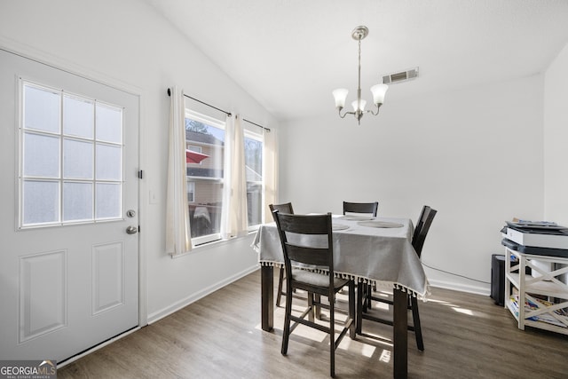 dining area featuring an inviting chandelier, dark wood-type flooring, and vaulted ceiling