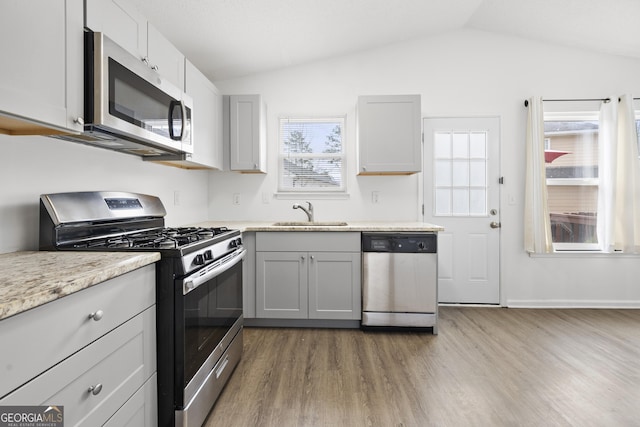 kitchen featuring stainless steel appliances, vaulted ceiling, sink, and gray cabinetry