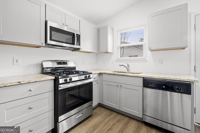 kitchen featuring wood-type flooring, appliances with stainless steel finishes, sink, and white cabinets