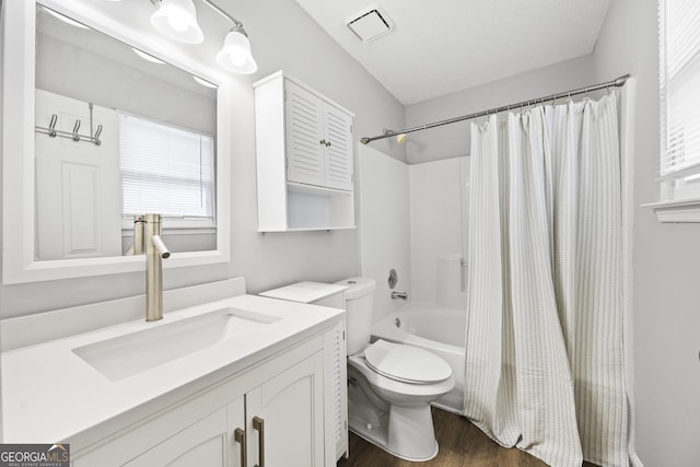 full bathroom with shower / tub combo with curtain, wood-type flooring, vanity, toilet, and a textured ceiling