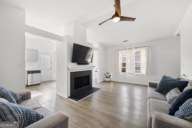 living room with vaulted ceiling, ceiling fan, and light wood-type flooring