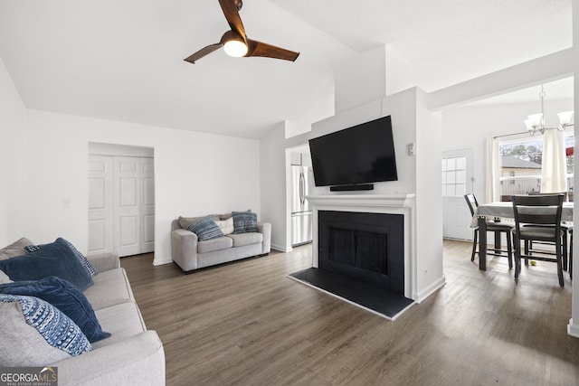 living room featuring lofted ceiling, dark hardwood / wood-style flooring, and ceiling fan with notable chandelier