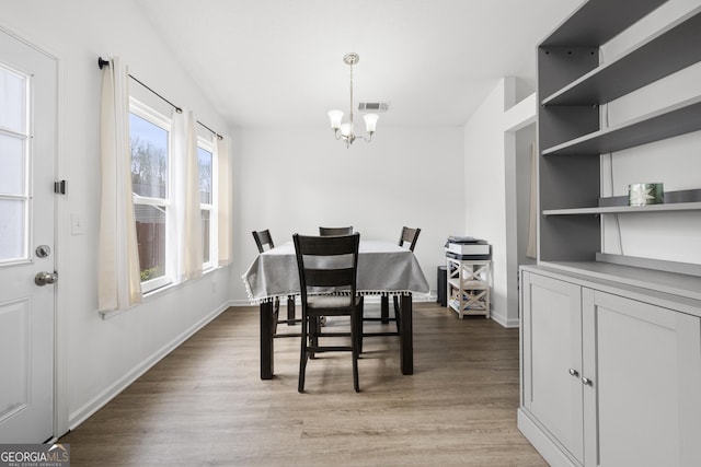 dining area with built in shelves, light hardwood / wood-style flooring, and a notable chandelier