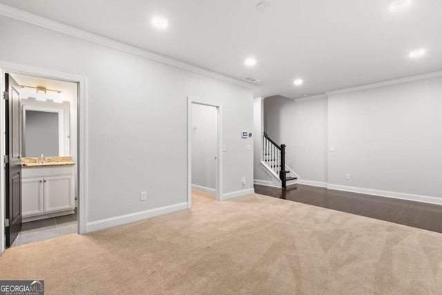 basement with crown molding, sink, and light carpet