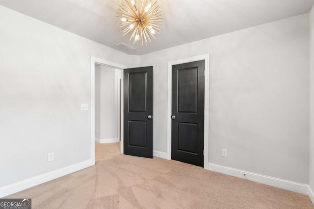 unfurnished bedroom featuring light colored carpet and a notable chandelier