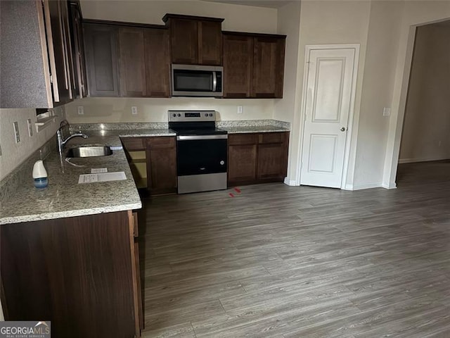 kitchen featuring light stone countertops, sink, dark brown cabinetry, and appliances with stainless steel finishes