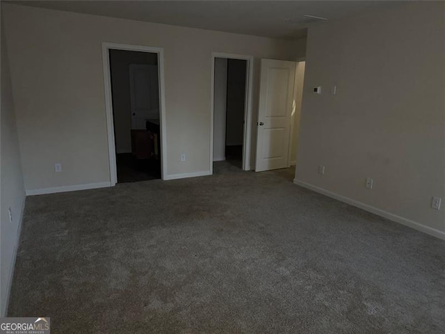 unfurnished bedroom with carpet, ensuite bathroom, and a walk in closet