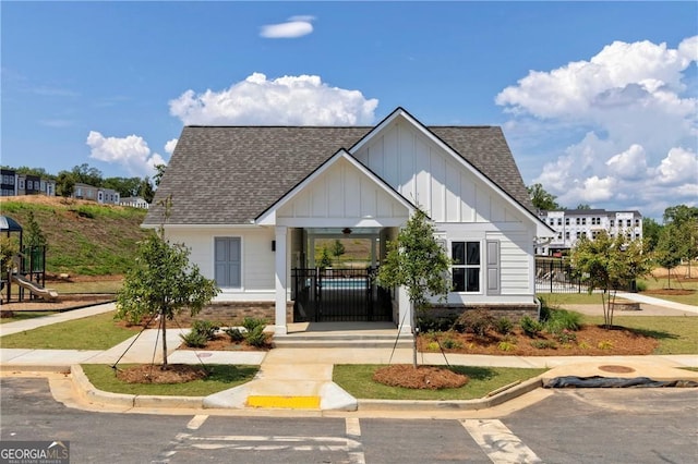 view of front of home featuring roof with shingles, brick siding, board and batten siding, and fence