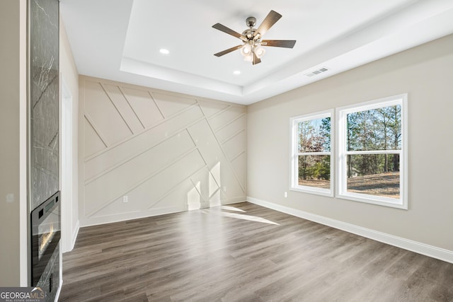 526 Whirlway St, Jefferson, GA 30549 - unfurnished living room featuring a tray ceiling, a decorative wall, wood finished floors, baseboards, and a ceiling fan