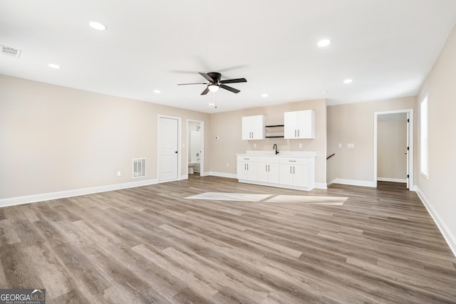 unfurnished living room with light hardwood / wood-style floors, sink, and ceiling fan