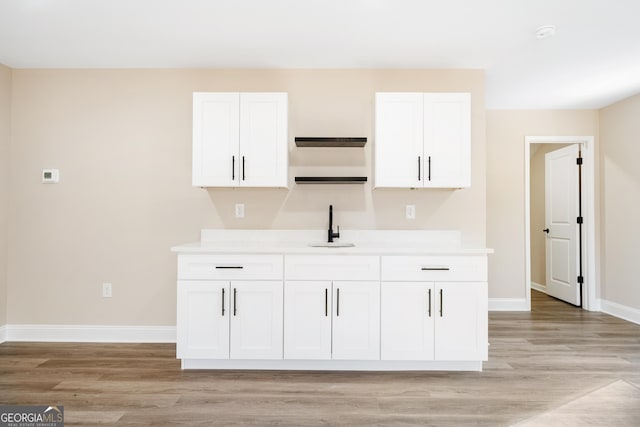 kitchen with white cabinets, light wood-type flooring, and sink