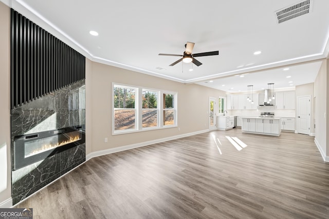 unfurnished living room featuring light wood-type flooring, ceiling fan, and a high end fireplace