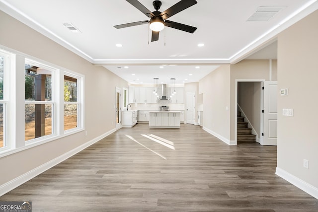 unfurnished living room featuring ceiling fan, sink, and light wood-type flooring