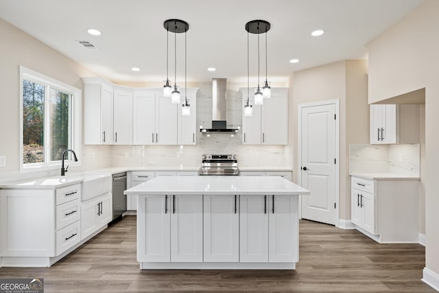 kitchen with white cabinets, a center island, wall chimney exhaust hood, and stainless steel appliances