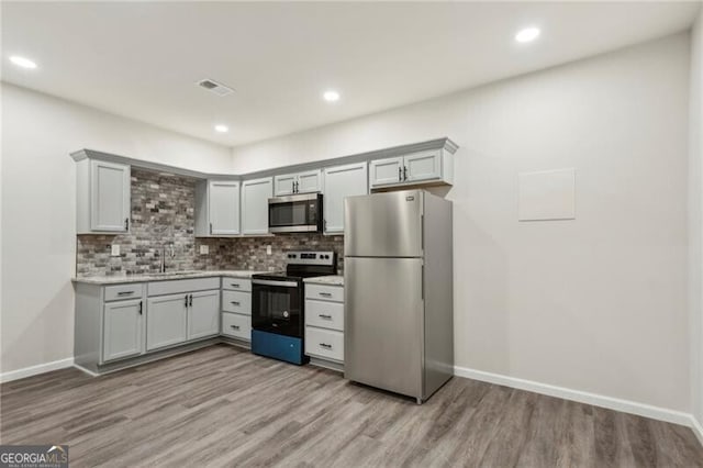 kitchen with sink, light wood-type flooring, tasteful backsplash, and stainless steel appliances