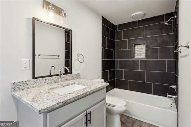 full bathroom with hardwood / wood-style floors, toilet, vanity, and tiled shower / bath