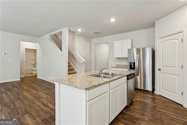 kitchen with appliances with stainless steel finishes, sink, white cabinetry, light stone counters, and a kitchen island with sink