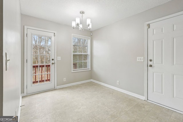 doorway to outside featuring a textured ceiling and a notable chandelier