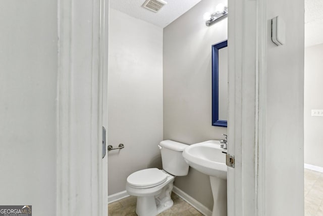 bathroom featuring a textured ceiling and toilet