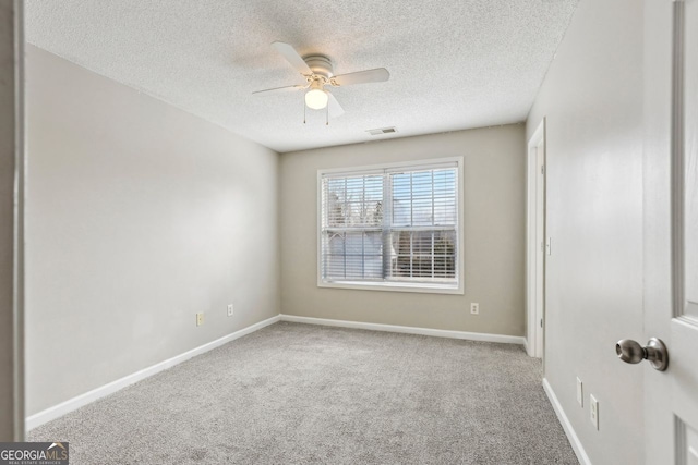 spare room with a textured ceiling, light colored carpet, and ceiling fan