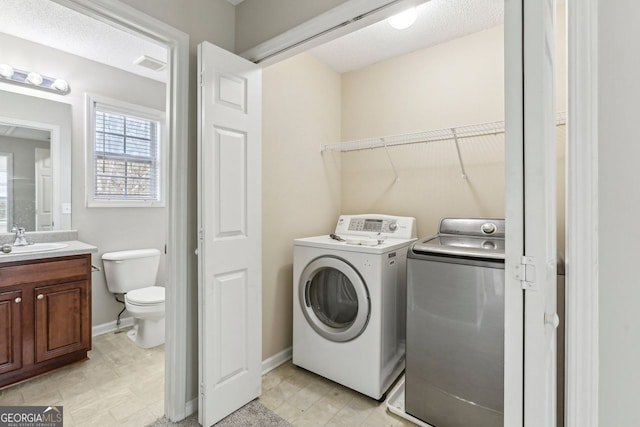 laundry area with sink, a textured ceiling, and washer and clothes dryer