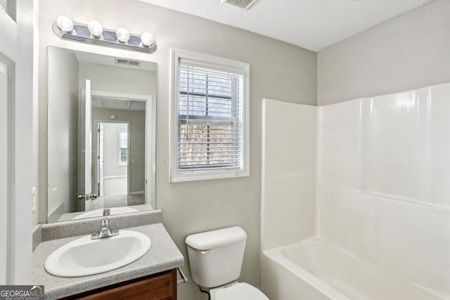 full bathroom with vanity, tub / shower combination, a textured ceiling, and toilet