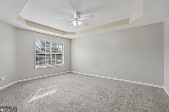 carpeted spare room featuring ceiling fan, a tray ceiling, and a textured ceiling