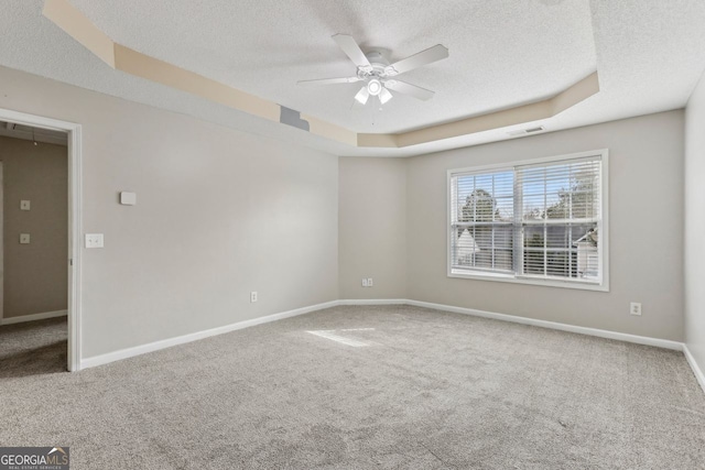 carpeted spare room with a raised ceiling, ceiling fan, and a textured ceiling