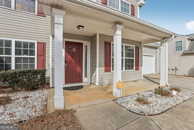 view of exterior entry with a garage and covered porch