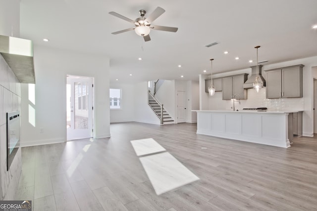 unfurnished living room with sink, ceiling fan, and light hardwood / wood-style flooring