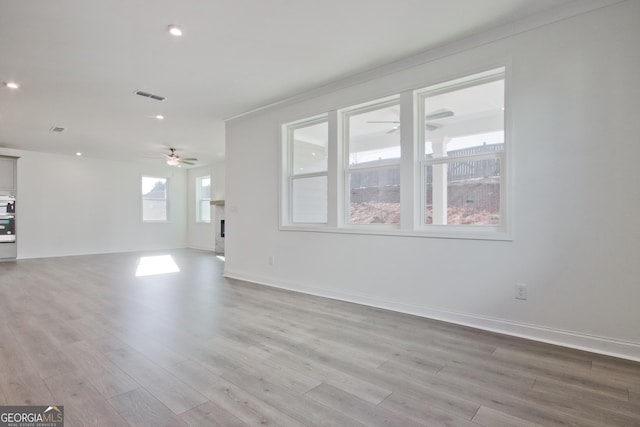 unfurnished living room featuring ornamental molding, ceiling fan, and light hardwood / wood-style flooring