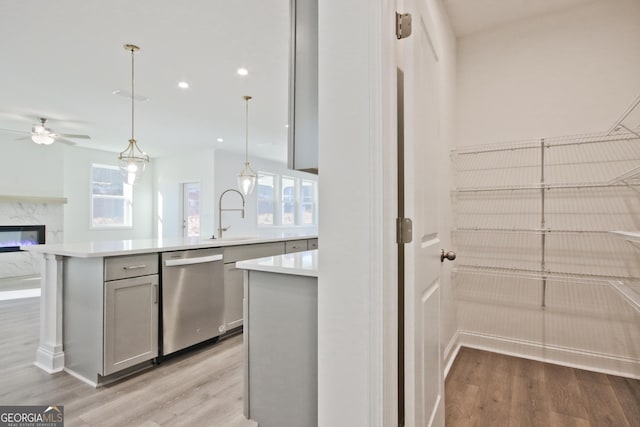 kitchen featuring a high end fireplace, dishwasher, decorative light fixtures, gray cabinets, and light wood-type flooring