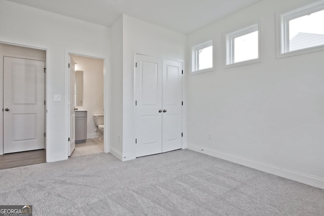 unfurnished bedroom featuring connected bathroom and light colored carpet