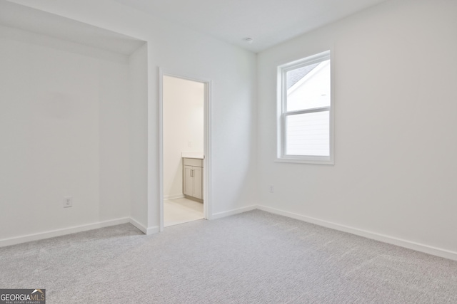 unfurnished bedroom with light colored carpet and ensuite bath