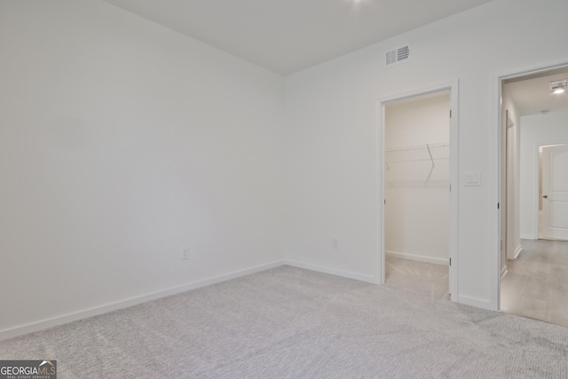 unfurnished bedroom featuring light carpet, a closet, and a walk in closet