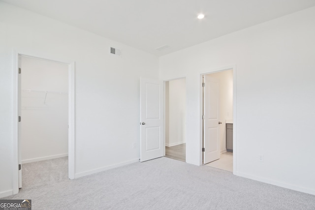 unfurnished bedroom featuring light colored carpet, a closet, and a walk in closet