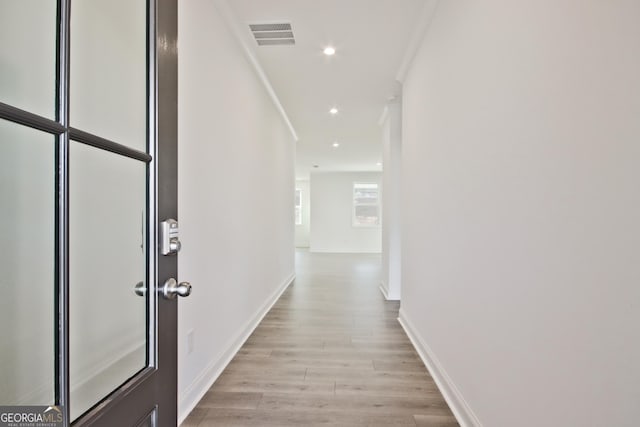 hall with crown molding and light hardwood / wood-style floors