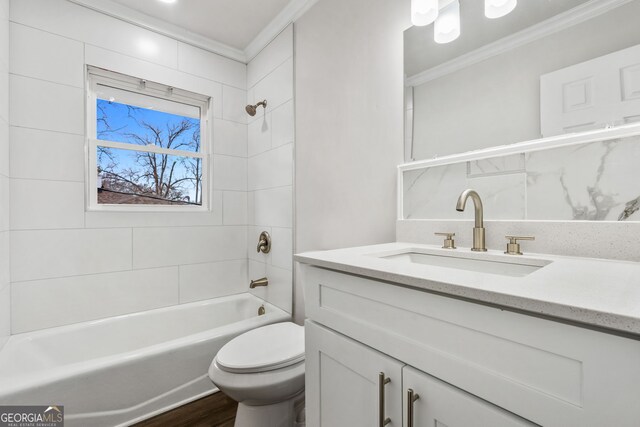 full bathroom featuring tiled shower / bath, hardwood / wood-style floors, ornamental molding, toilet, and vanity