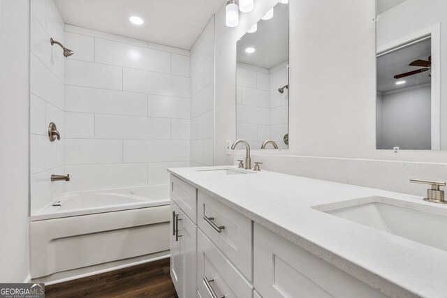 bathroom with ceiling fan, wood-type flooring, tiled shower / bath combo, and vanity