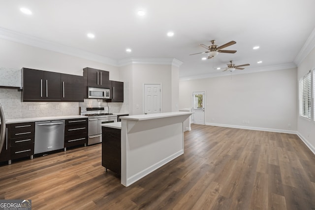 kitchen featuring crown molding, appliances with stainless steel finishes, decorative backsplash, a kitchen island, and dark hardwood / wood-style flooring