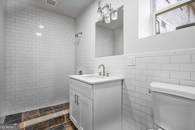 bathroom with vanity, walk in shower, tile walls, and toilet