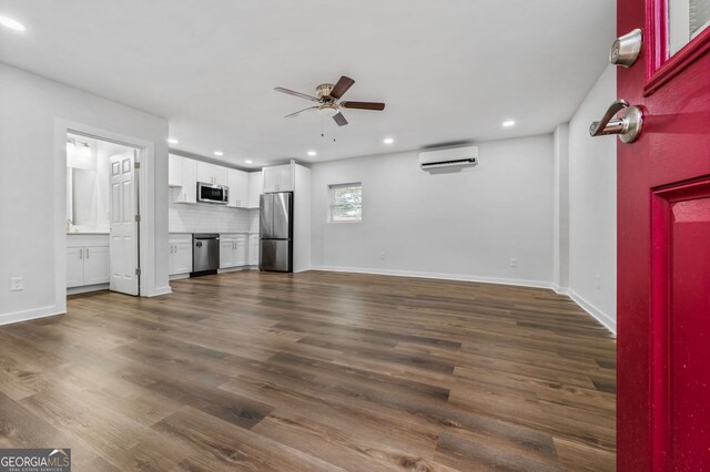 unfurnished living room featuring a wall mounted air conditioner, ceiling fan, and dark hardwood / wood-style flooring