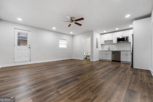 unfurnished living room with ceiling fan and dark wood-type flooring