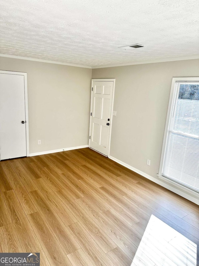 spare room featuring light hardwood / wood-style floors and a textured ceiling