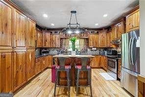 kitchen featuring pendant lighting, a center island, range, a breakfast bar, and stainless steel refrigerator