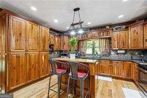 kitchen with hanging light fixtures, light wood-type flooring, stove, a kitchen bar, and a center island