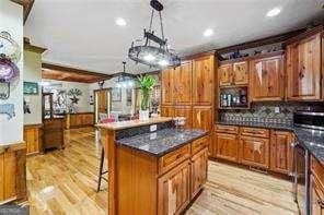 kitchen featuring light hardwood / wood-style floors, decorative backsplash, a kitchen breakfast bar, a kitchen island, and decorative light fixtures